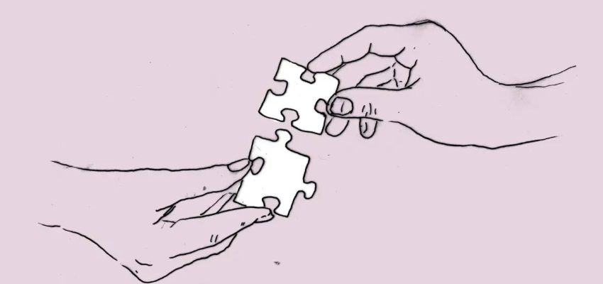 Grafika przedstawia narysowane cienką kreską dwie dłonie trzymające po jednym kawałku puzzla. Puzzle są przedstawione w taki sposób, że niemal się łączą.