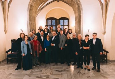 Kilkonaścioro osób w różnym wieku, ubranych elegancji, stoi na tle portalu gotyckiego we wrocławskim Ratuszu.