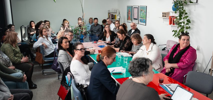 Zdjęcie przedstawia kilkanaście osób zebranych w Przejściu Dialogu, siedzących wokół długiego stołu.